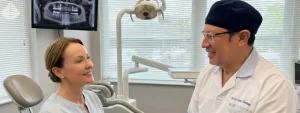 Dr Aristo Carranza discussing pain-free dental implants with a smiling patient in Westfield NJ