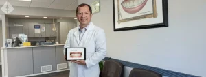 Dr. Aristo Carranza holding a tablet with a digital smile design in his Westfield dental office.